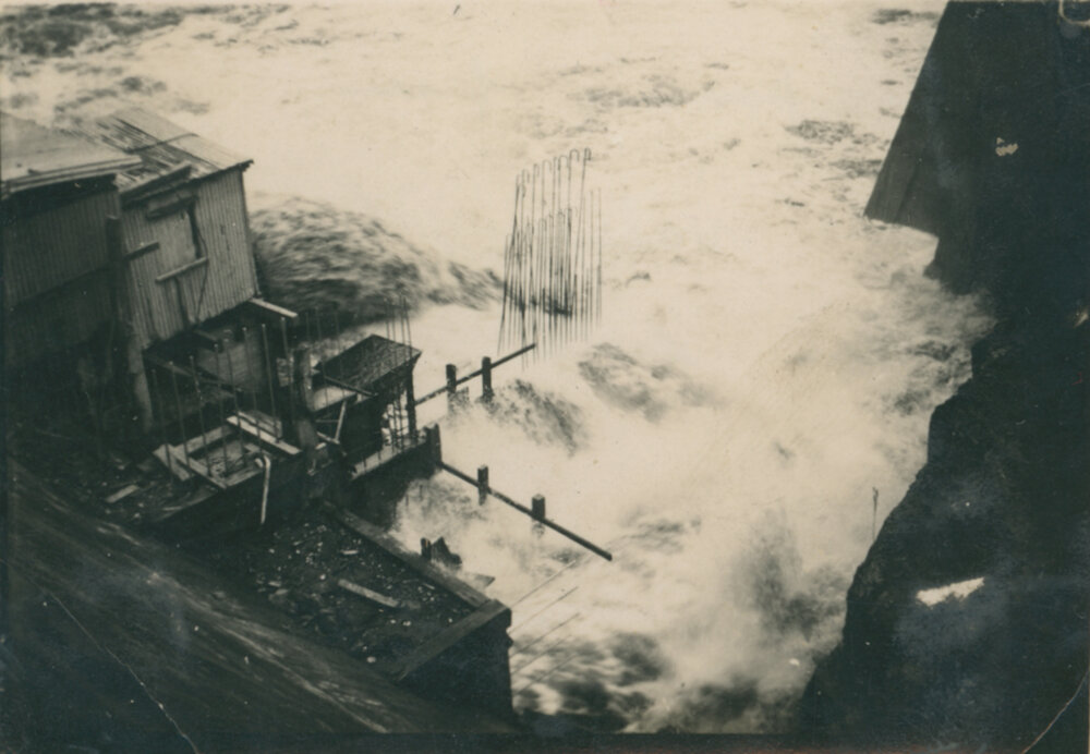 Water pouring from needle valves on the hydroelectric side of dam wall.