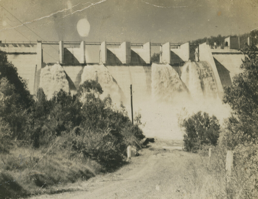 River in flood with water pouring over top of wall