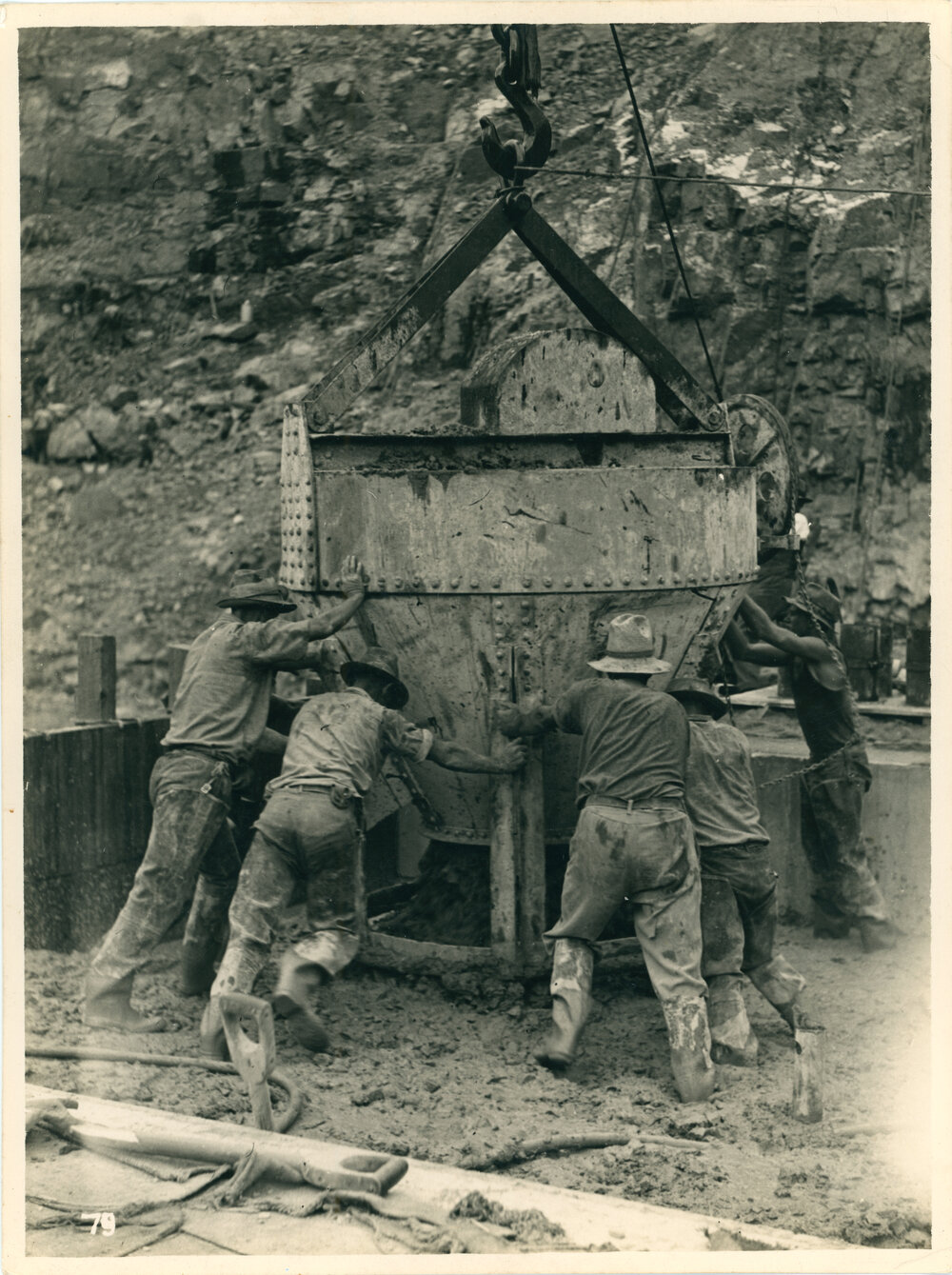 Workers pouring concrete from a bucket hoisted on a cable