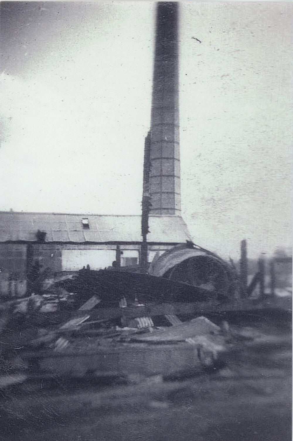Demolished condensery building with brick chimney standing behind