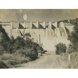 River in flood with water pouring over top of wall