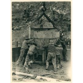 Workers pouring concrete from a bucket hoisted on a cable